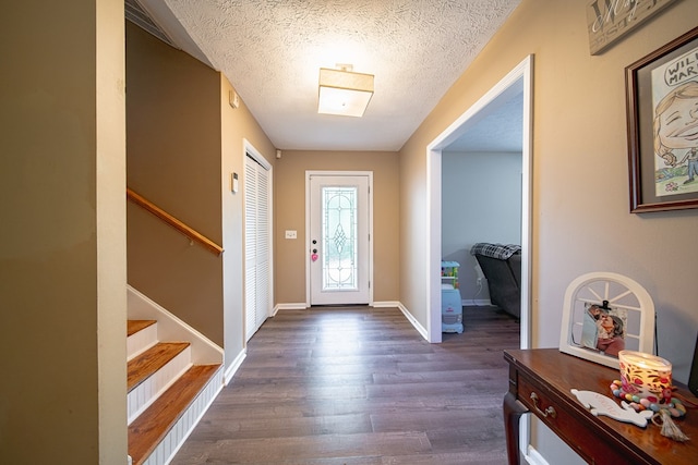 foyer featuring dark wood-style floors, stairway, a textured ceiling, and baseboards