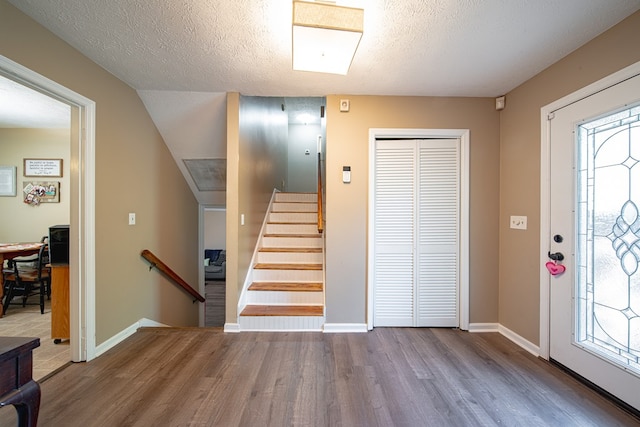 entryway with baseboards, wood finished floors, a textured ceiling, and plenty of natural light