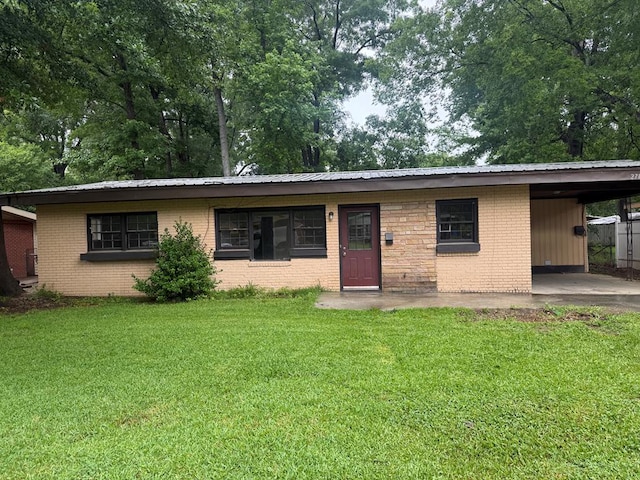 ranch-style house featuring a front lawn, a carport, metal roof, and brick siding