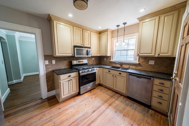 kitchen featuring sink, hanging light fixtures, light wood-type flooring, stainless steel appliances, and backsplash