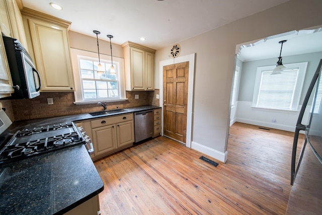 kitchen with appliances with stainless steel finishes, decorative light fixtures, light hardwood / wood-style floors, and sink