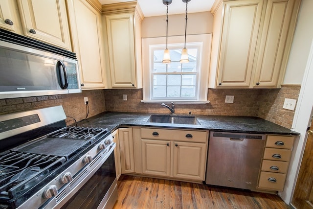 kitchen with sink, decorative light fixtures, light hardwood / wood-style flooring, stainless steel appliances, and decorative backsplash