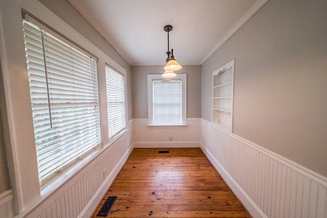 unfurnished dining area with crown molding, wood-type flooring, and built in features