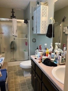 bathroom featuring a stall shower, a textured ceiling, vanity, and toilet