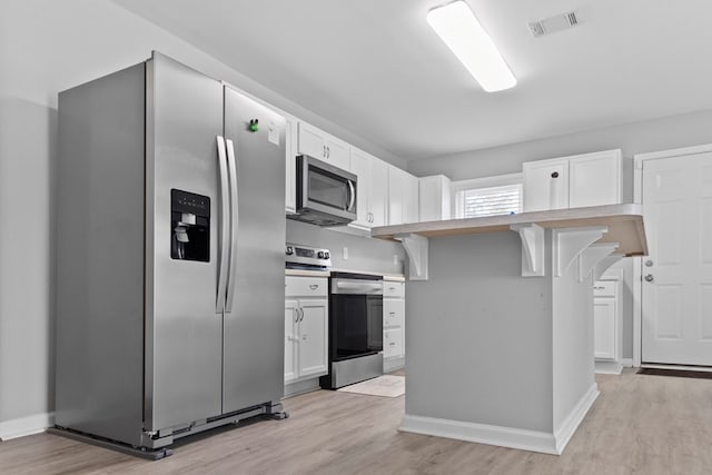 kitchen featuring white cabinetry, appliances with stainless steel finishes, and a kitchen breakfast bar