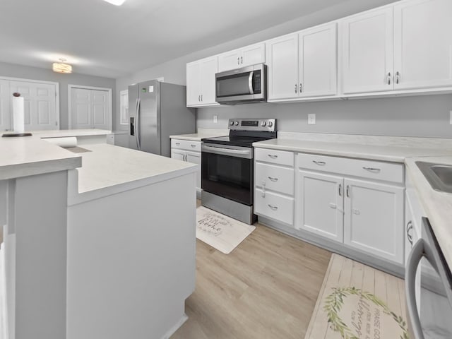 kitchen with white cabinetry, appliances with stainless steel finishes, sink, and light wood-type flooring