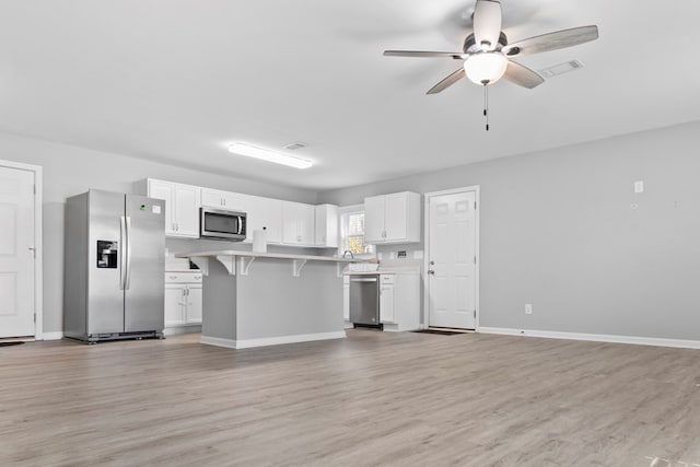 kitchen with white cabinetry, light wood-type flooring, a breakfast bar area, and appliances with stainless steel finishes