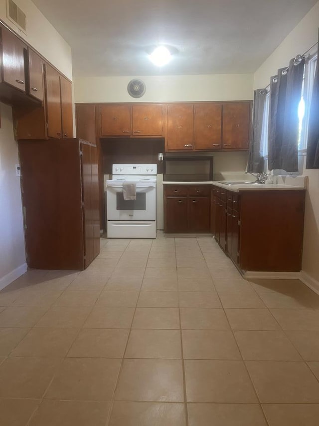 kitchen with white range oven, light tile patterned floors, and sink