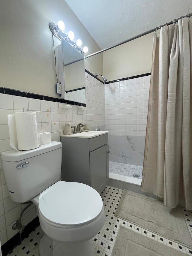 bathroom with vanity, tile patterned floors, a shower with shower curtain, toilet, and tile walls