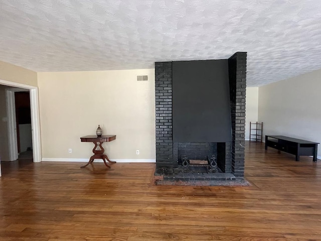 unfurnished living room featuring a fireplace, a textured ceiling, and hardwood / wood-style flooring