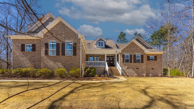 view of front of home with crawl space, brick siding, a porch, and a front yard