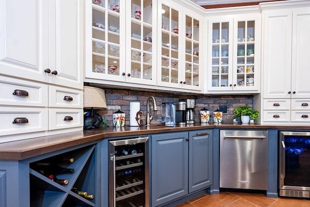 bar with white cabinetry, stainless steel dishwasher, and beverage cooler