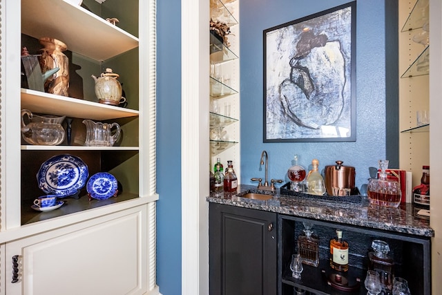 bar with sink and dark stone countertops