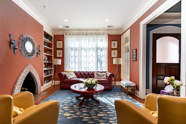 living area with ornamental molding, a brick fireplace, and built in shelves