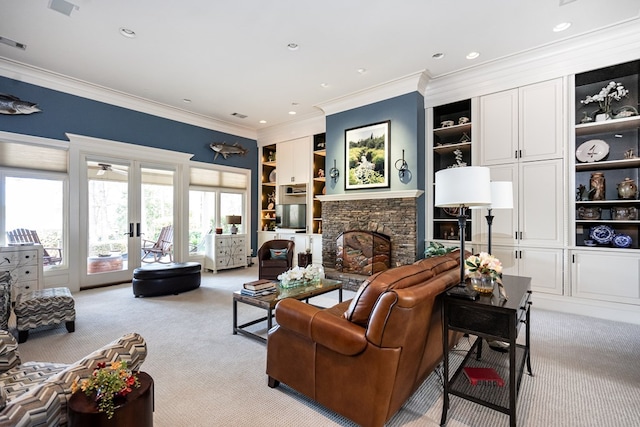 living room featuring built in shelves, french doors, a stone fireplace, crown molding, and light colored carpet