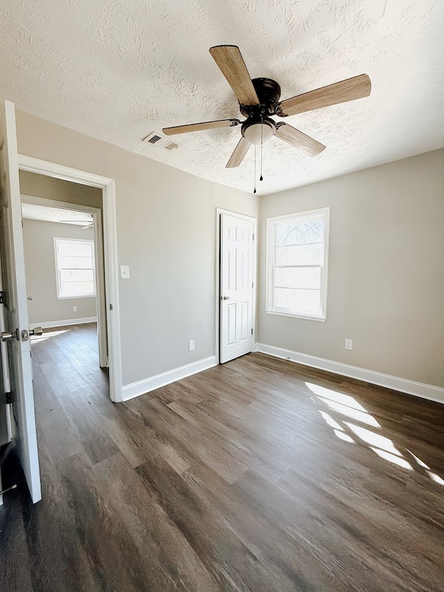 spare room with baseboards, a textured ceiling, and dark wood finished floors