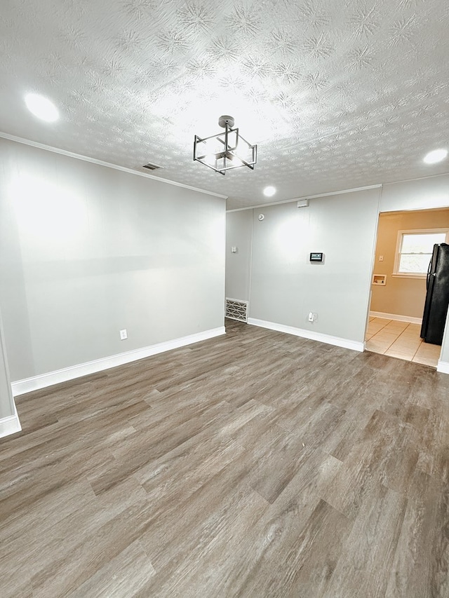 spare room featuring a textured ceiling, baseboards, and wood finished floors