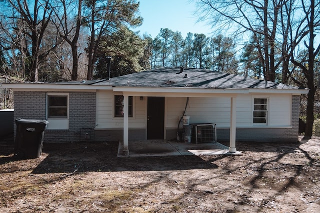 back of house featuring cooling unit and brick siding