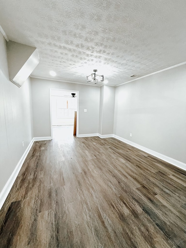 interior space with baseboards, a textured ceiling, wood finished floors, and crown molding