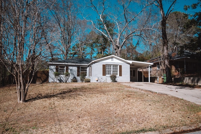 ranch-style home featuring a carport, fence, brick siding, and driveway