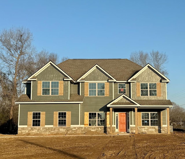 craftsman-style house featuring stone siding and a shingled roof