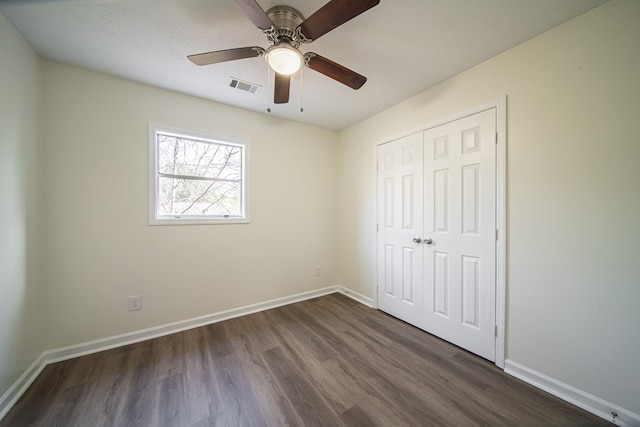 unfurnished bedroom with dark wood-type flooring, ceiling fan, and a closet