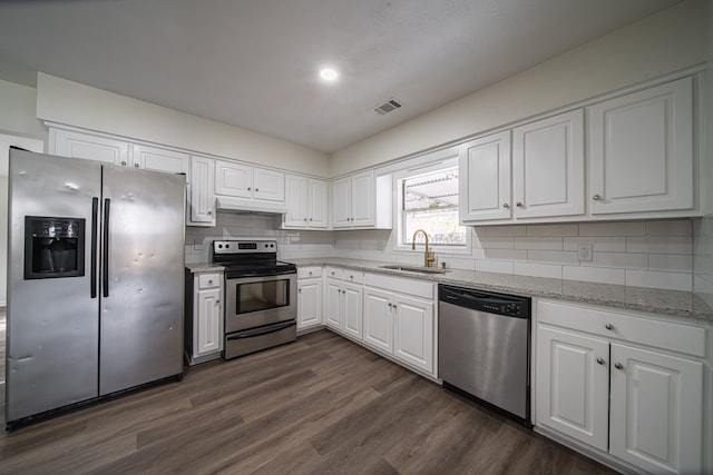 kitchen with appliances with stainless steel finishes, dark hardwood / wood-style floors, sink, backsplash, and white cabinets