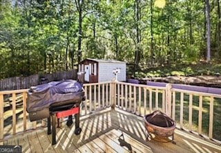 wooden terrace featuring a fire pit and a storage shed