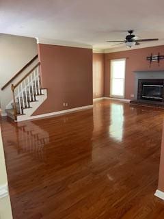 unfurnished living room with crown molding, dark wood-type flooring, and ceiling fan