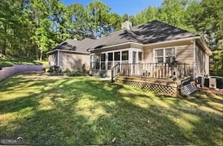 back of house featuring a yard, a deck, and a sunroom