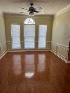 unfurnished room featuring wood-type flooring, ornamental molding, ceiling fan, and a textured ceiling