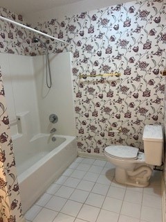 bathroom featuring tile patterned floors, toilet, and bathing tub / shower combination