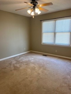 carpeted empty room with ceiling fan and a textured ceiling