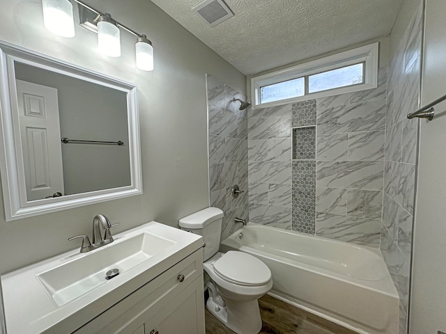 full bathroom featuring vanity, tiled shower / bath combo, toilet, a textured ceiling, and wood-type flooring