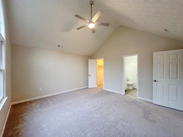 unfurnished bedroom featuring light carpet, high vaulted ceiling, ensuite bathroom, ceiling fan, and a textured ceiling