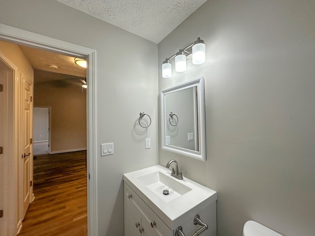 bathroom featuring hardwood / wood-style flooring, vanity, toilet, and a textured ceiling