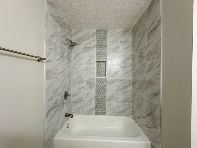 bathroom featuring tiled shower / bath combo and a textured ceiling