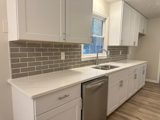 kitchen featuring white cabinetry, sink, stainless steel dishwasher, and a textured ceiling