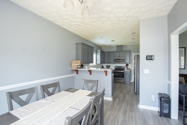 6074 White Pine Dr, Midland, GA 31820 - dining area with light wood finished floors, a textured ceiling, and a chandelier