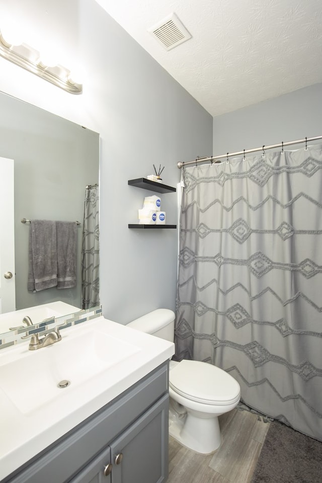 6074 White Pine Dr, Midland, GA 31820 - full bath featuring wood finished floors, vanity, a textured ceiling, and a shower with curtain