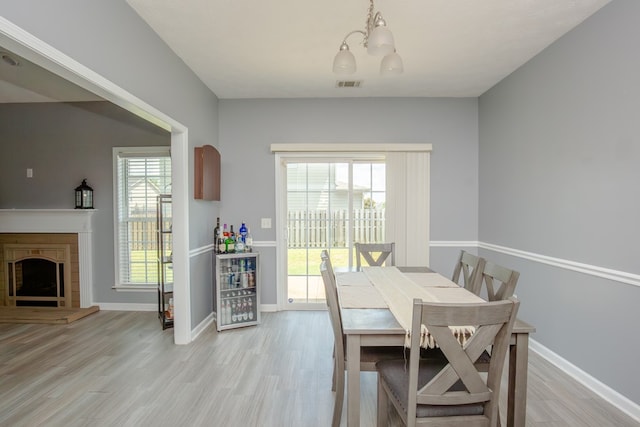 6074 White Pine Dr, Midland, GA 31820 - dining room with a chandelier, light wood-style flooring, and a fireplace with raised hearth