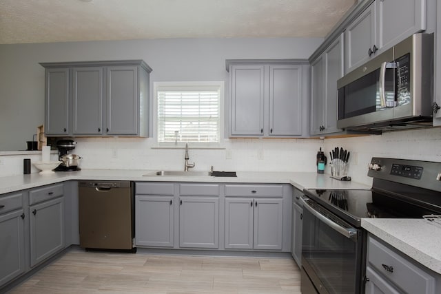 6074 White Pine Dr, Midland, GA 31820 - kitchen with stainless steel appliances, gray cabinets, light countertops, tasteful backsplash, and light wood-type flooring