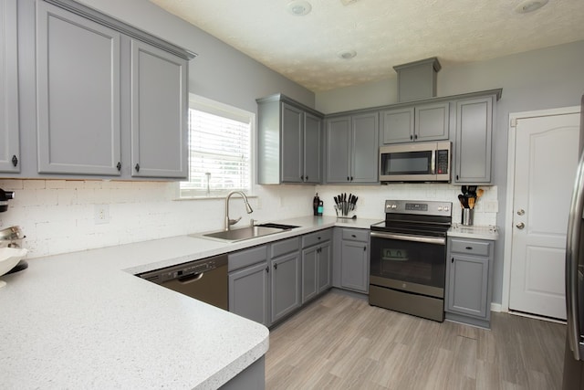 6074 White Pine Dr, Midland, GA 31820 - kitchen with stainless steel appliances, gray cabinetry, tasteful backsplash, light countertops, and light wood-style floors