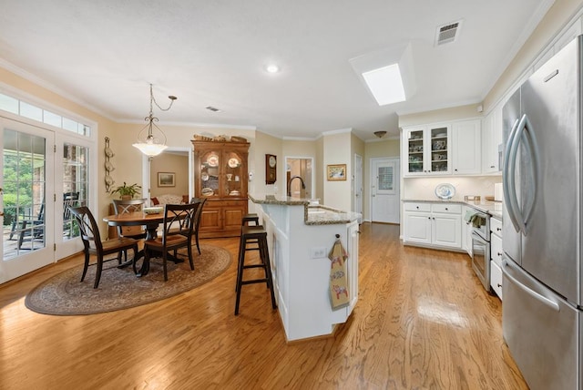 9011 Travelers Way, Midland, GA 31820 - kitchen with appliances with stainless steel finishes, light wood-style flooring, white cabinetry, a sink, and a breakfast bar