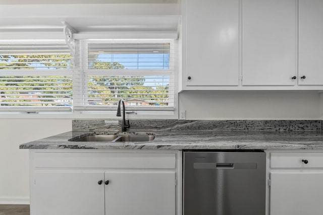 kitchen with stone counters, white cabinets, dishwasher, and a sink