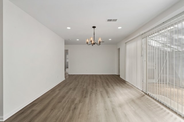 spare room with recessed lighting, visible vents, wood finished floors, a chandelier, and baseboards