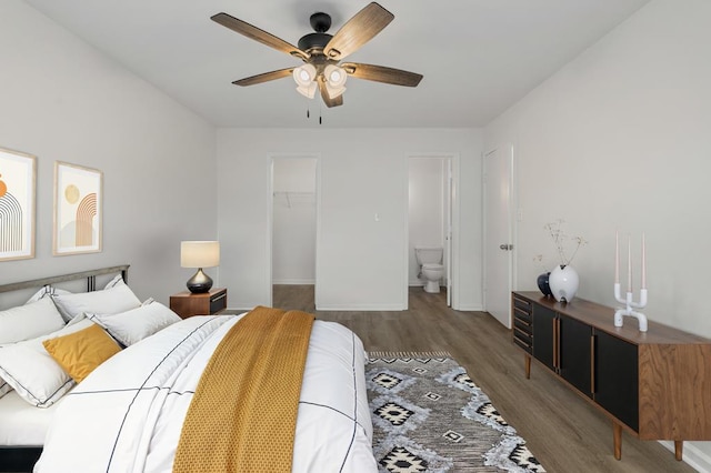 bedroom featuring a walk in closet, a closet, ceiling fan, wood finished floors, and baseboards