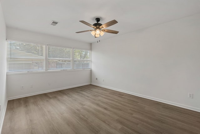 empty room featuring visible vents, baseboards, wood finished floors, and a ceiling fan