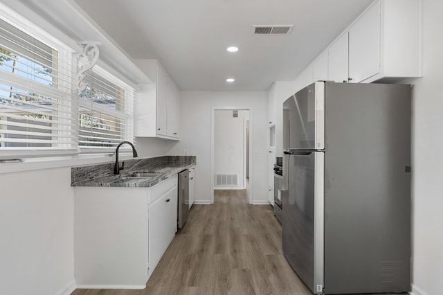 kitchen with a sink, white cabinets, visible vents, and stainless steel appliances