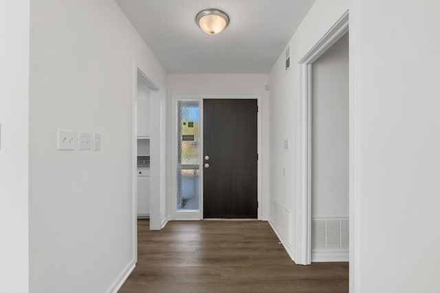 foyer with baseboards, visible vents, and dark wood-type flooring